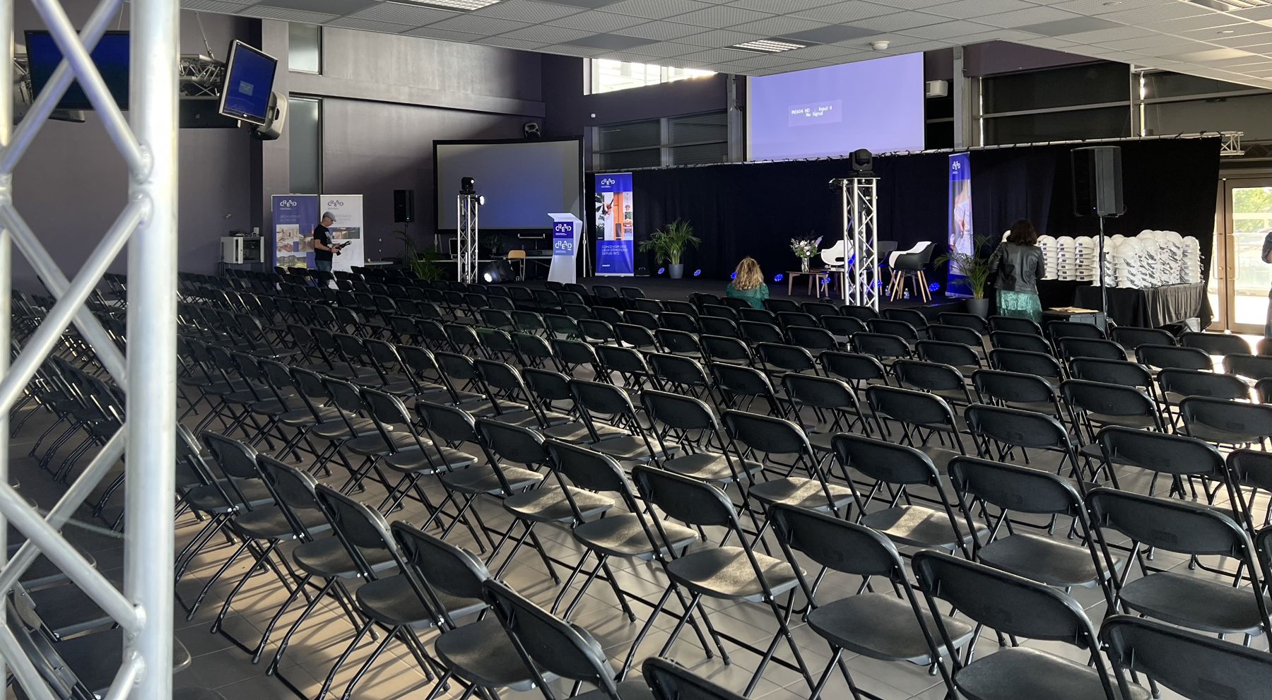 Salle de conférence équipée, chaises alignées face aux écrans