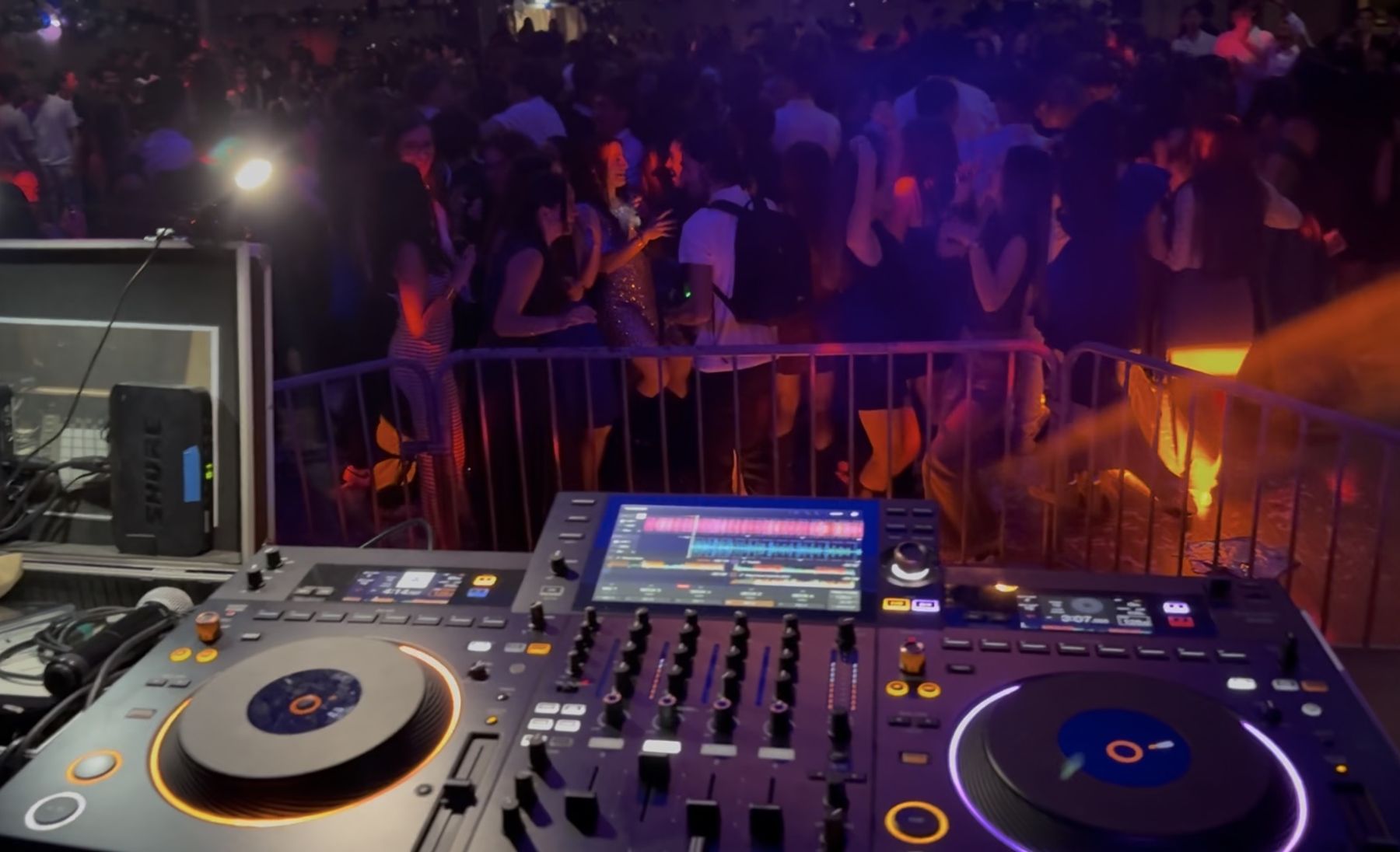 Platines et table de mixage face à une piste de danse animée