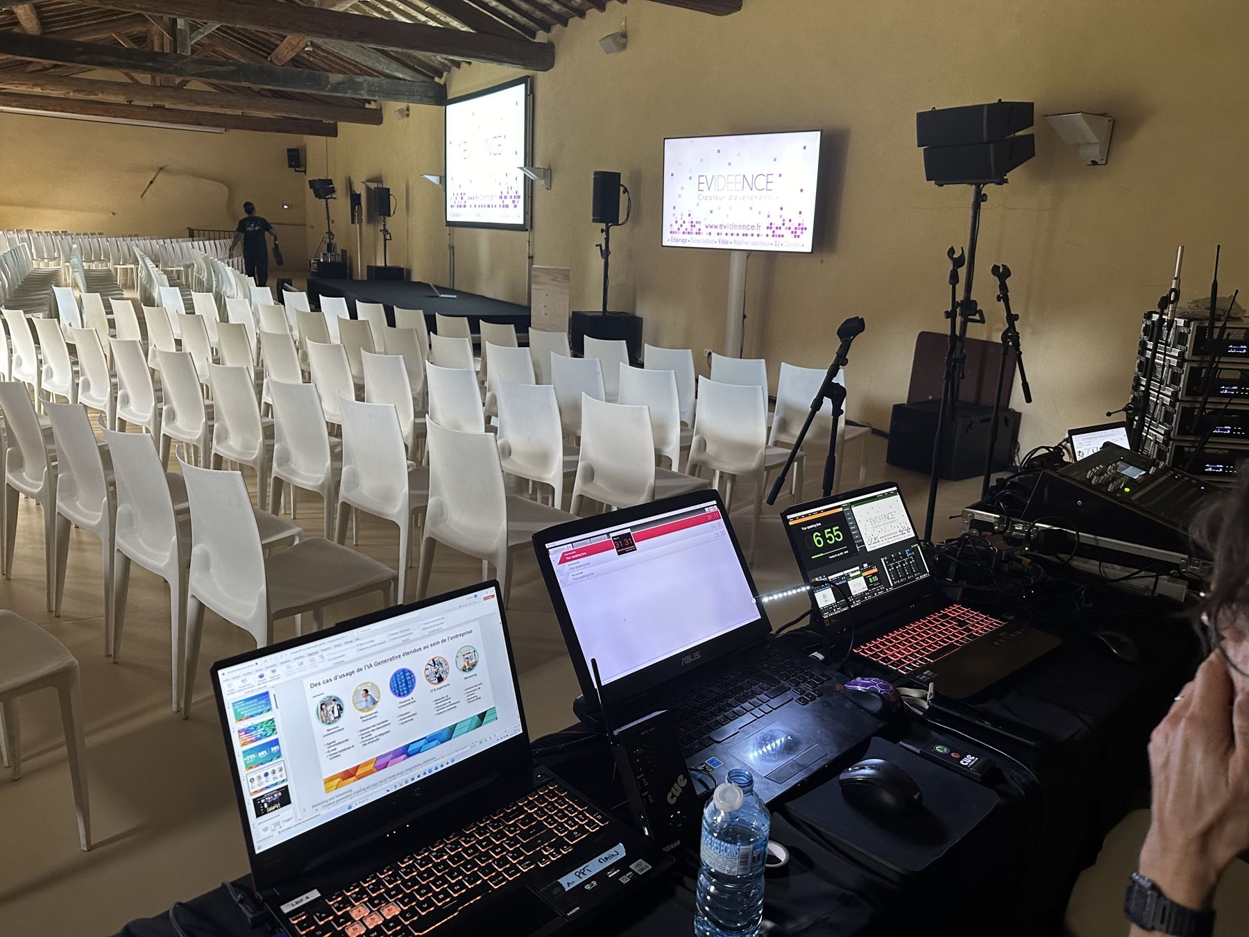 Régie technique et ordinateurs devant une salle de conférence